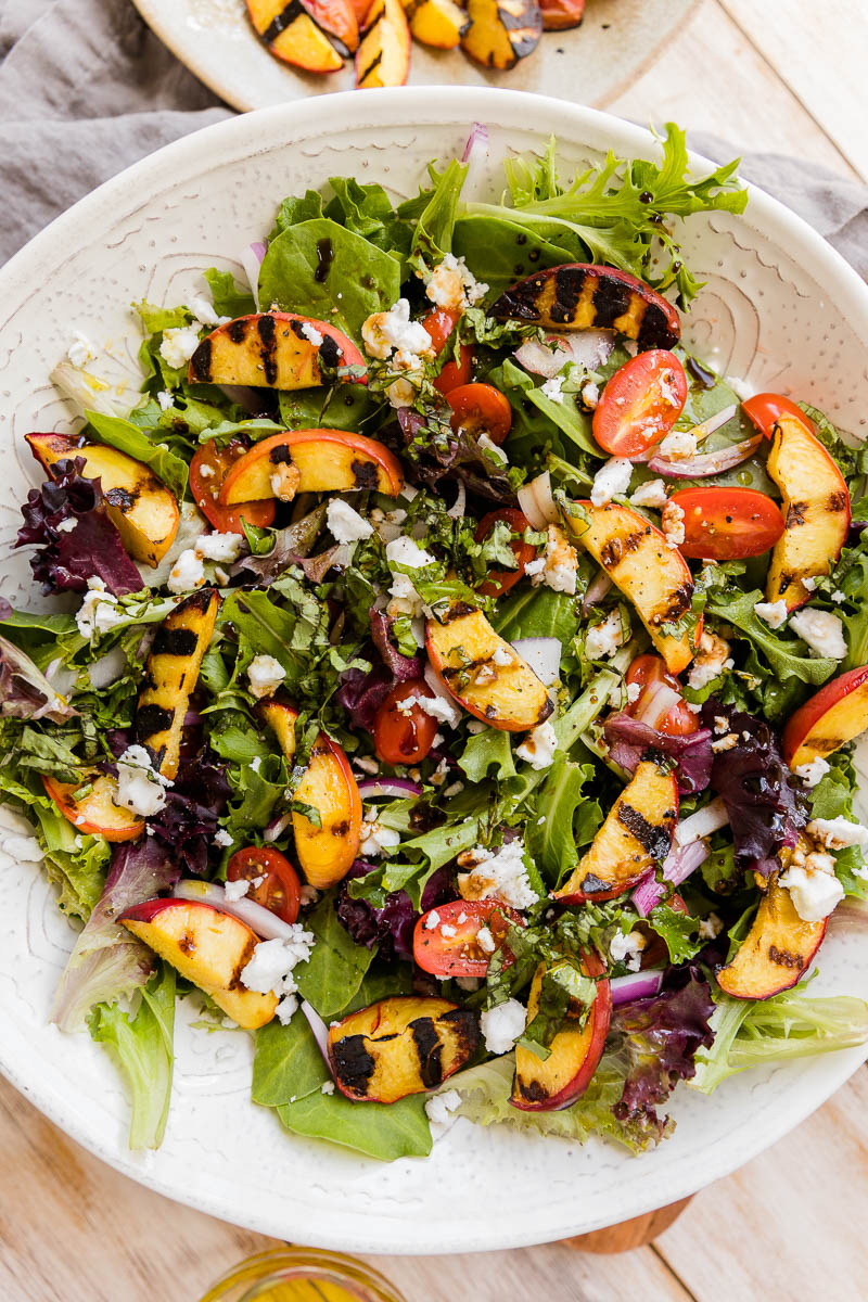 Finished grilled peach salad in white bowl.