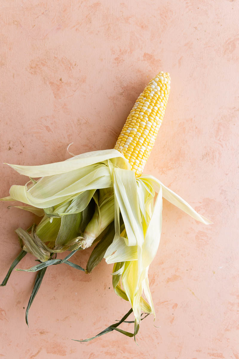 Corn on the cobb with husk peeled down.