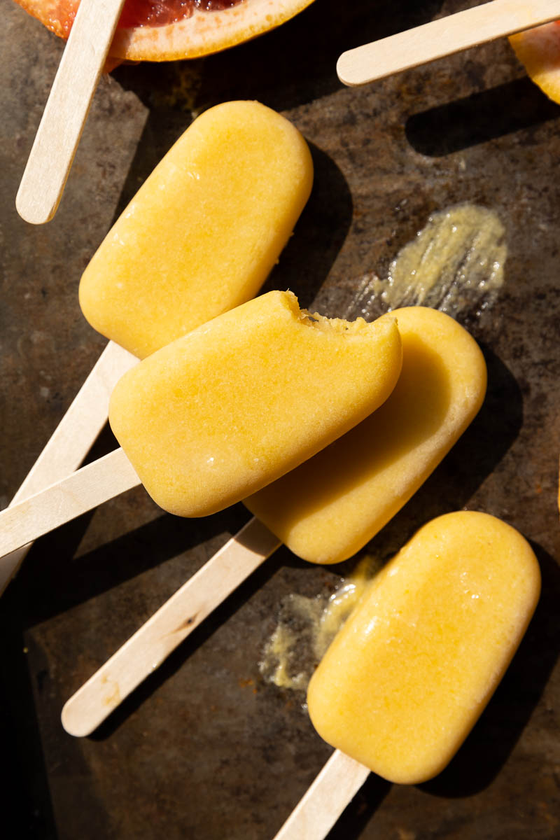 Bite taken out of orange protein popsicle.