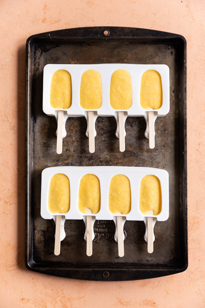 Frozen orange protein popsicles in molds.