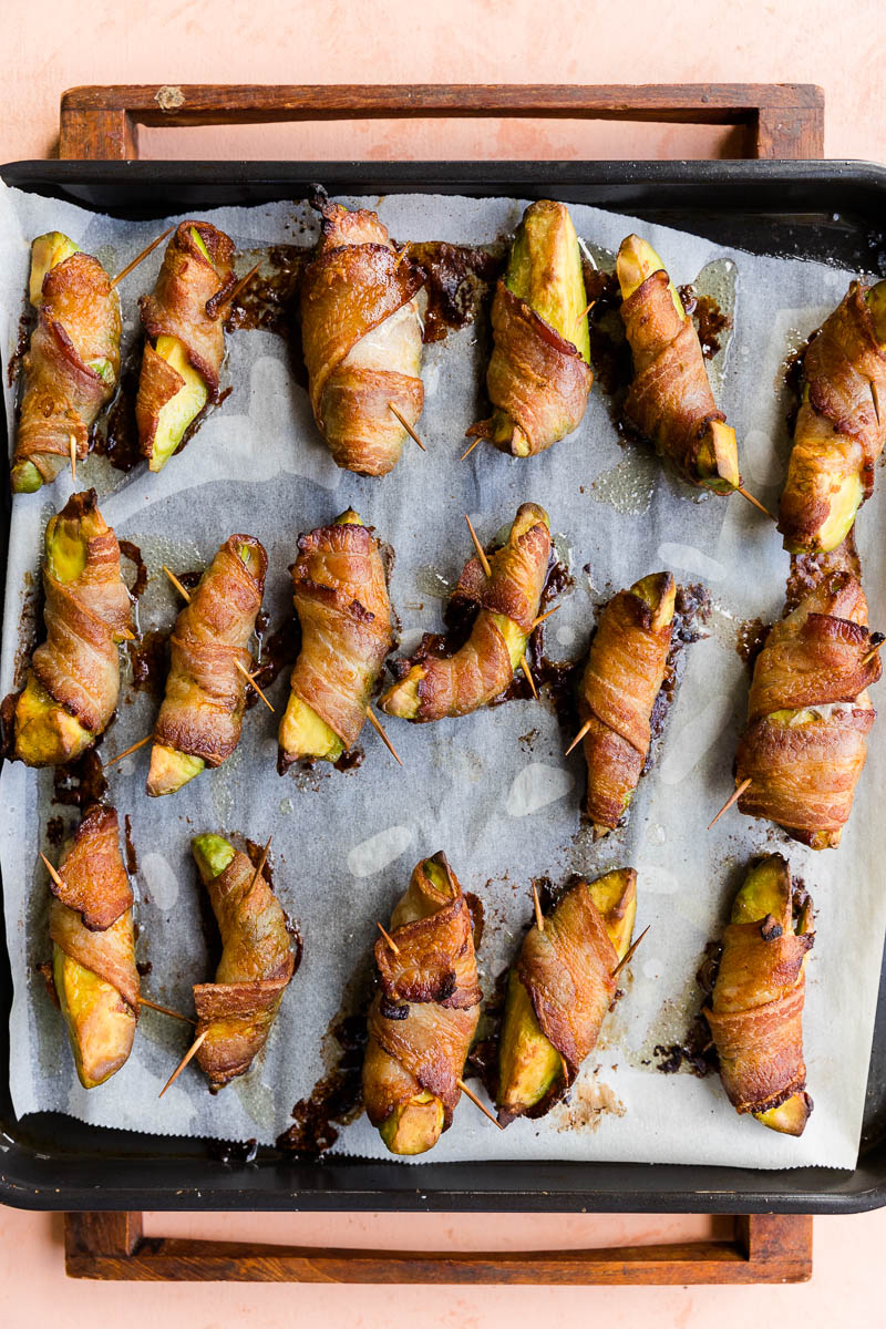 Crispy bacon wrapped avocado on a baking sheet.