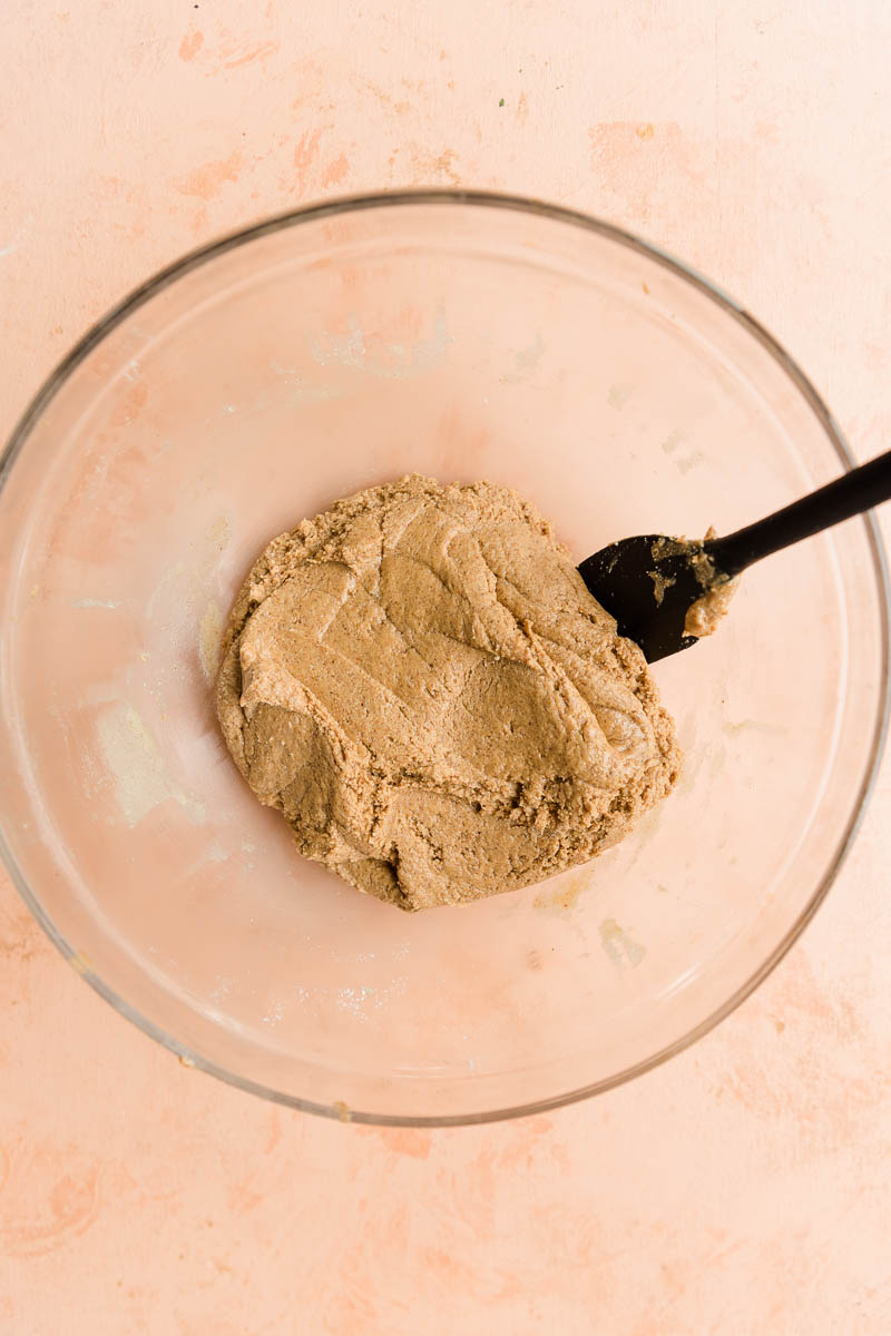 Cookie dough mixture in a mixing bowl with spatula on the side.