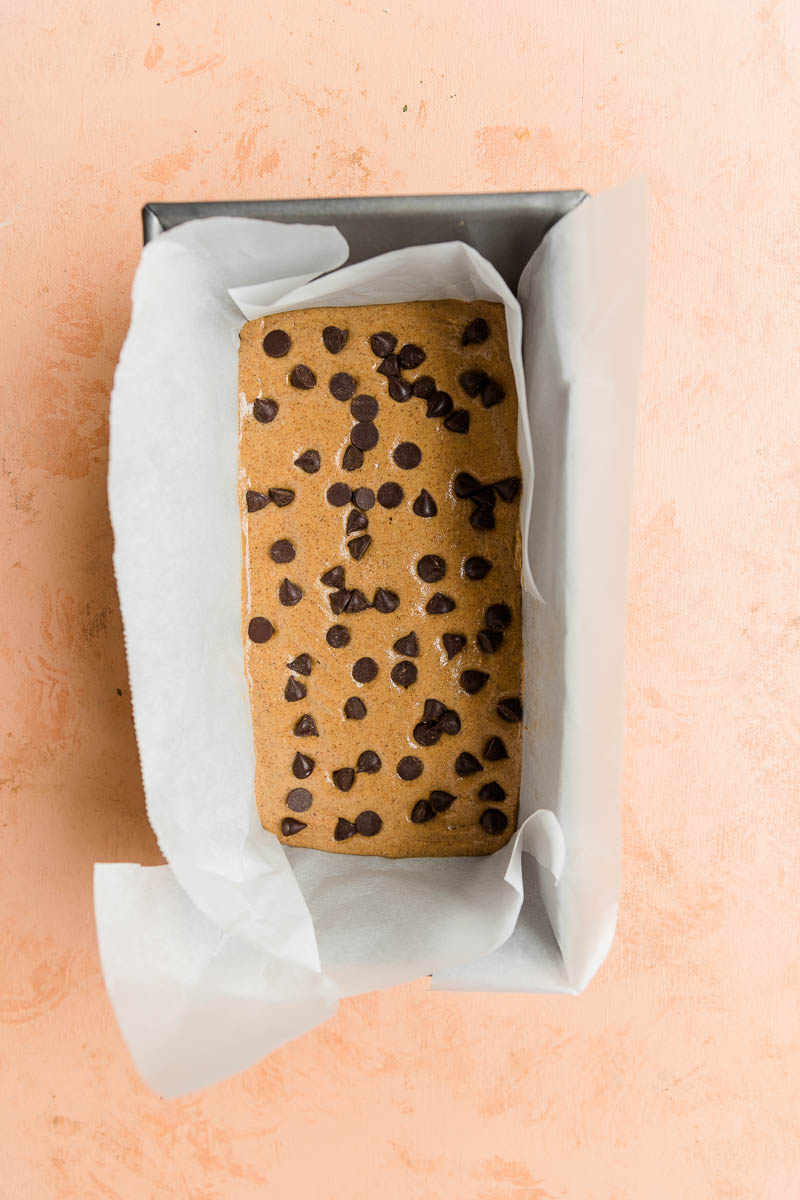 Cookie dough mixture in a parchment paper lined bread pan.
