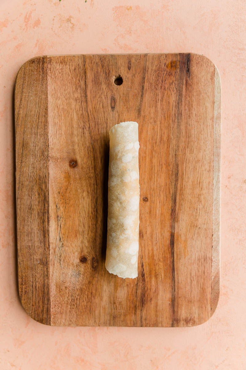 Tortilla wrapped up on a cutting board.