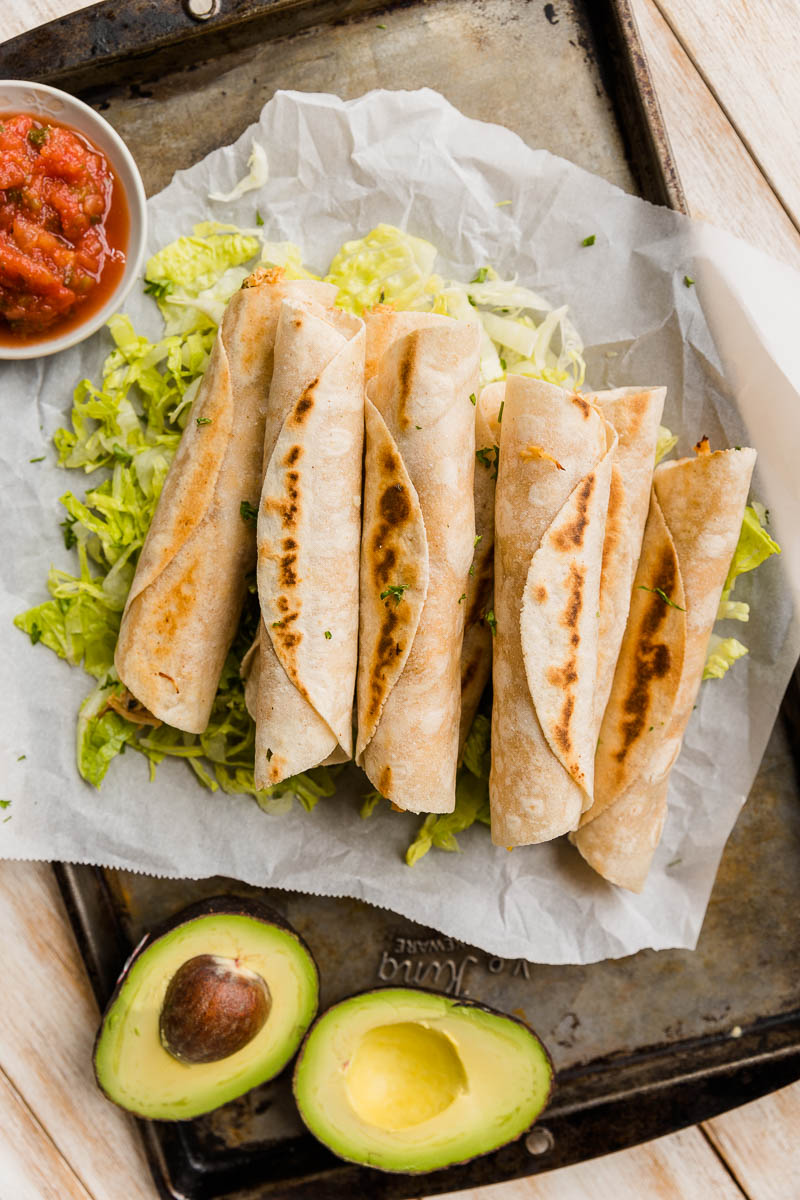 Taquitos on a bed of fresh lettuce.