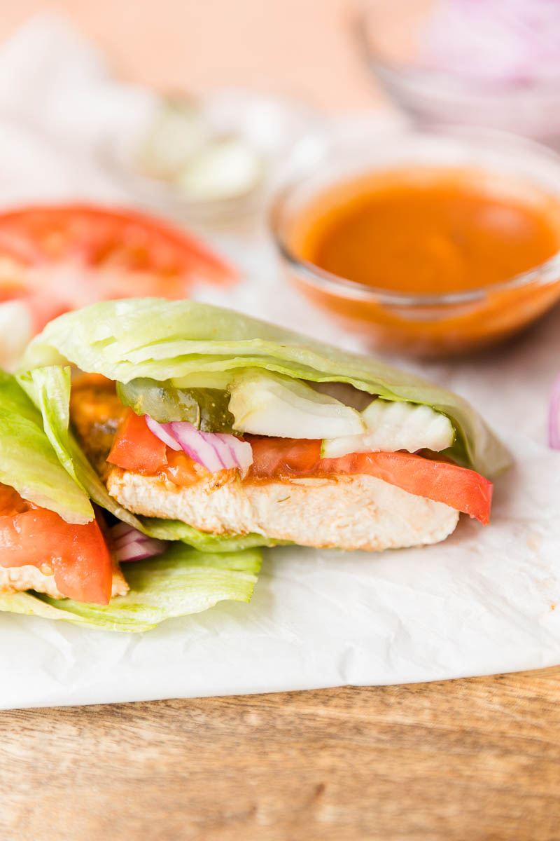 BBQ chicken sandwich cut in half with lettuce bun.