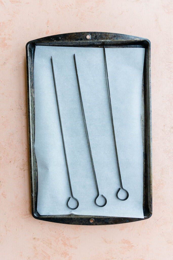 Skewers on a parchment paper lined baking sheet.