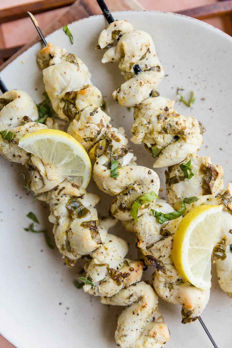 Lemon basil chicken skewers on a plate.