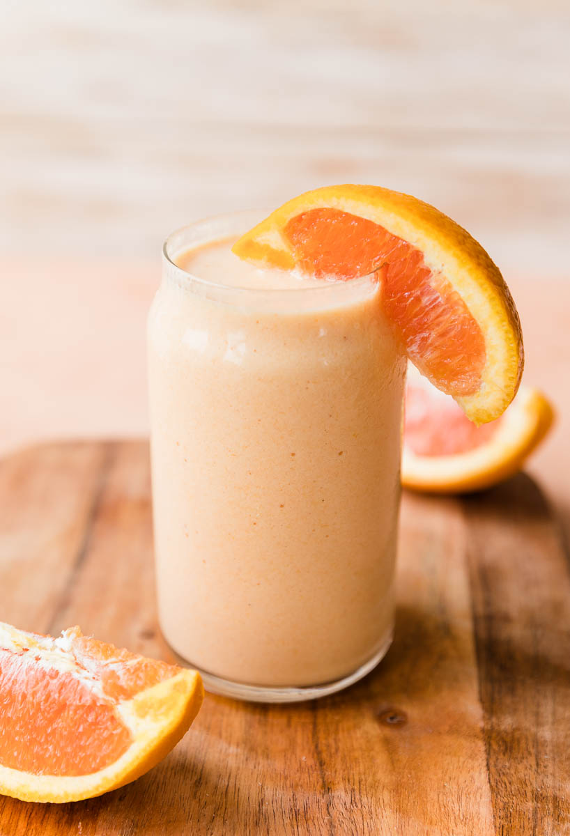 Orange smoothie with a slice of orange on the glass.