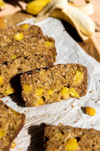 Pineapple coconut banana bread slice on parchment paper.