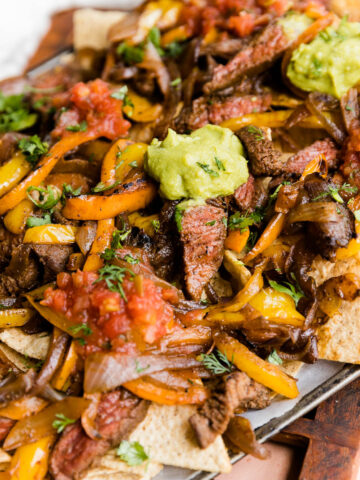Steak fajita nachos with guacamole and salsa on top.