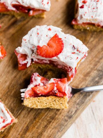 Strawberry shortcake bar on a wood board with a big bite on a fork.