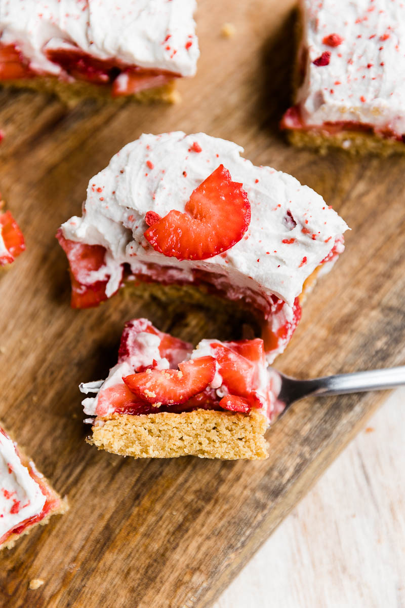 Strawberry shortcake bar on a wood board with a big bite on a fork.