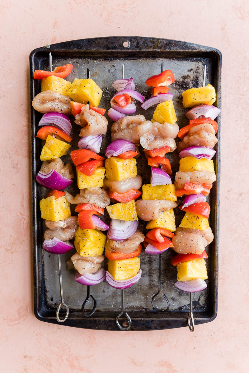 Uncooked teriyaki chicken skewers on a baking sheet.