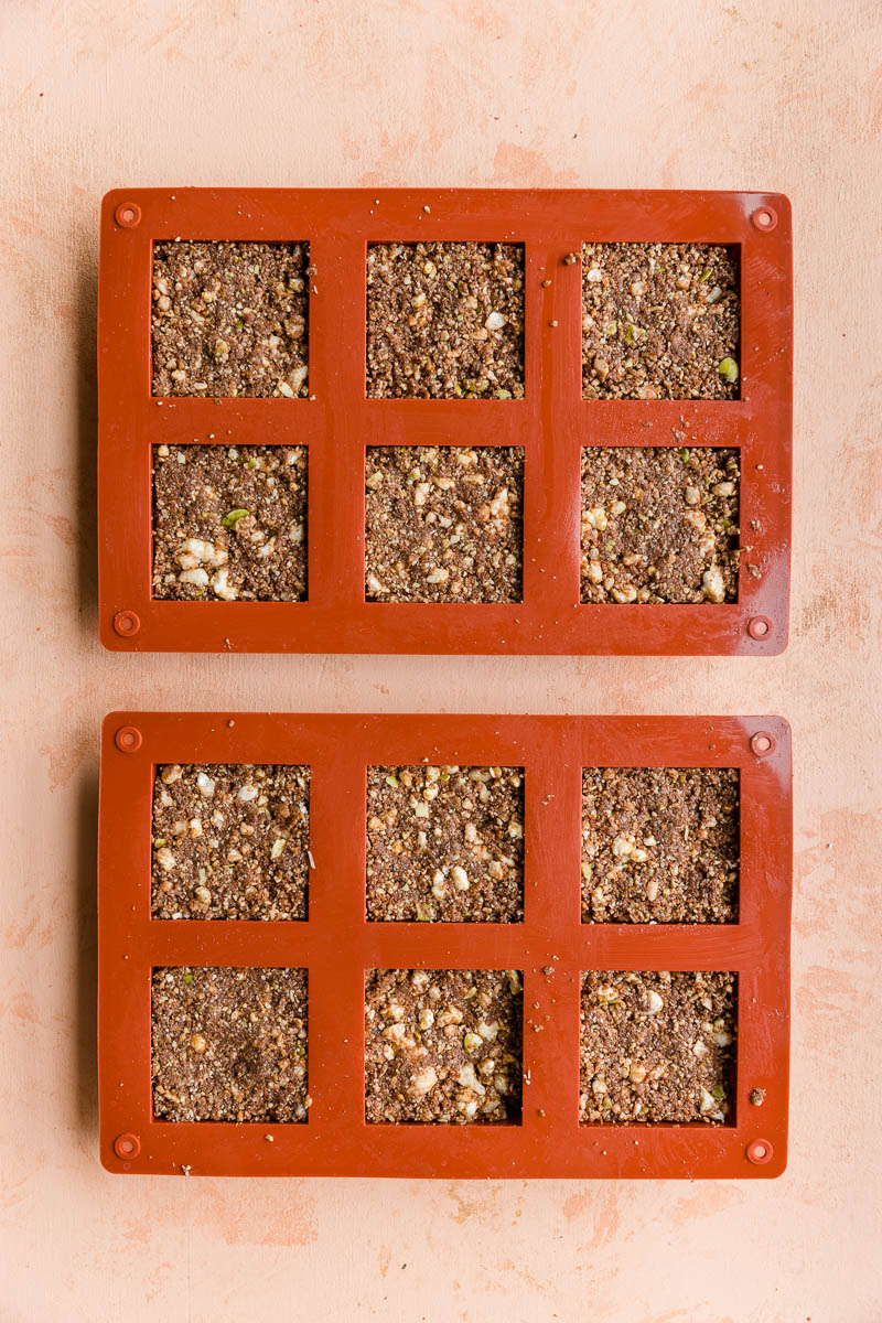 Chocolate mixture pressed into small square silicone molds.