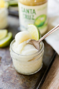Lime sorbet in cup with spoon leaning on the side.