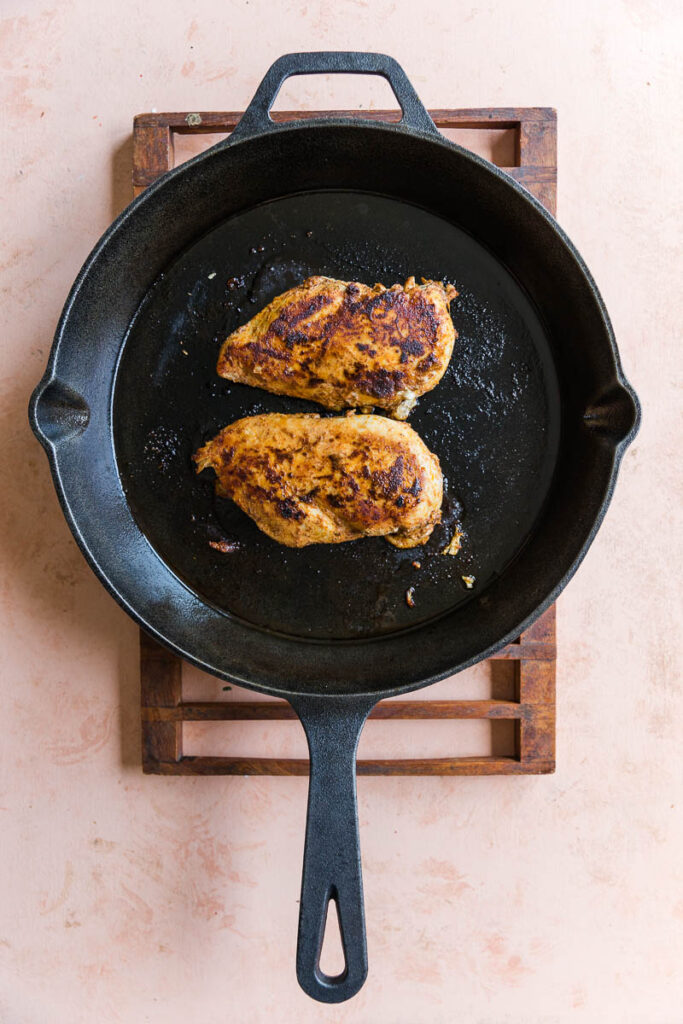 Cooked chicken breast in cast iron skillet.