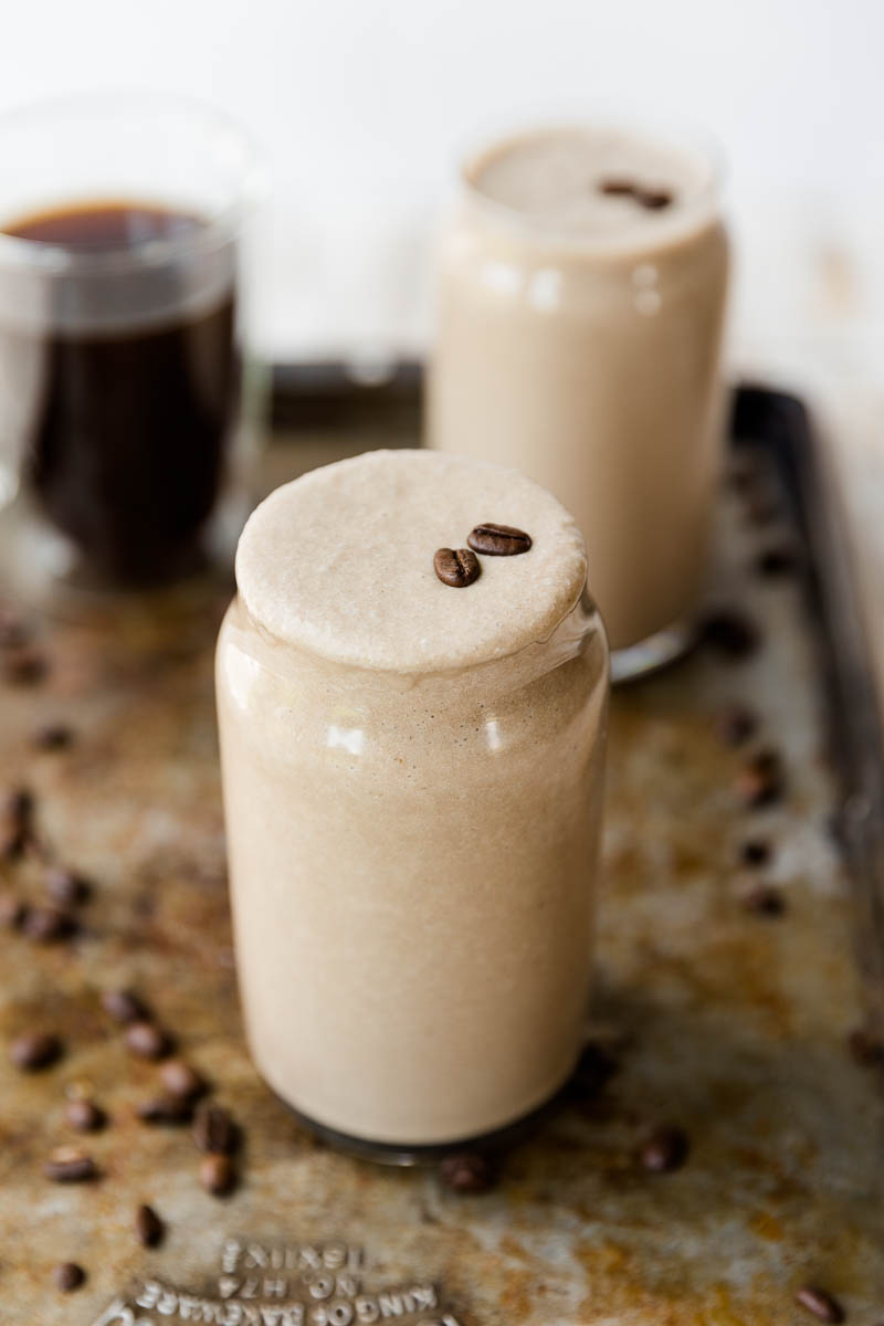 Coffee milkshake in a glass cup with coffee beans on top.