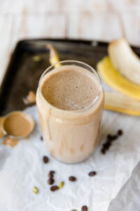 Coffee banana smoothie with banana peel behind the cup.