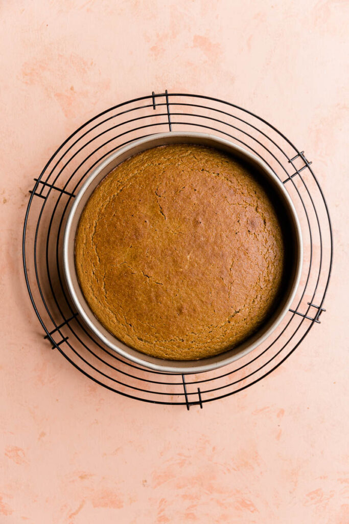 Vanilla cake cooling on metal rack.