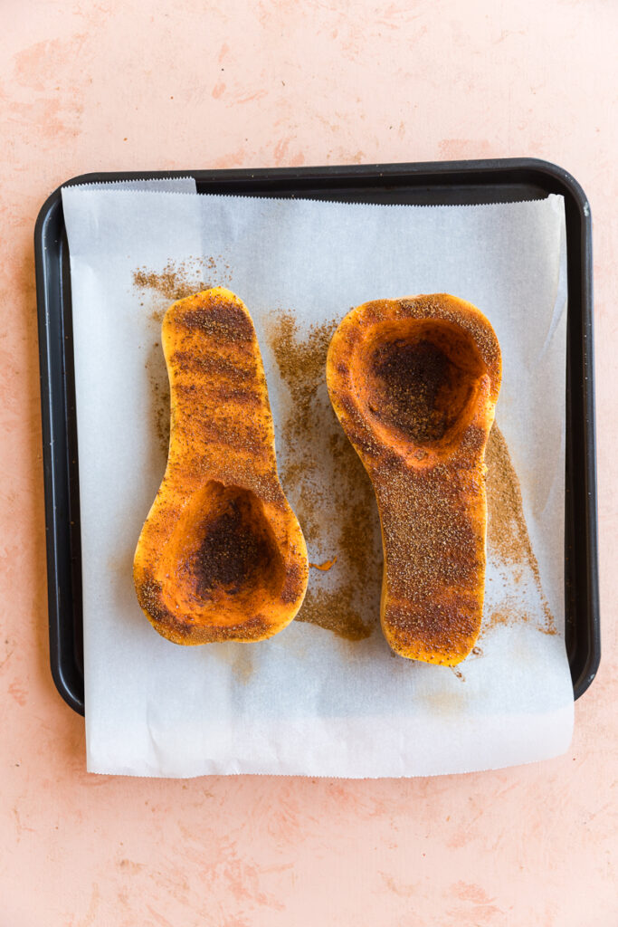 Butternut squash halves with sprinkled cinnamon and sugar mixture.