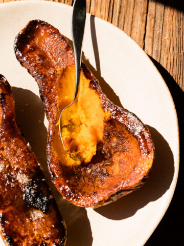 Spoon scooping out caramelized butternut squash halves.