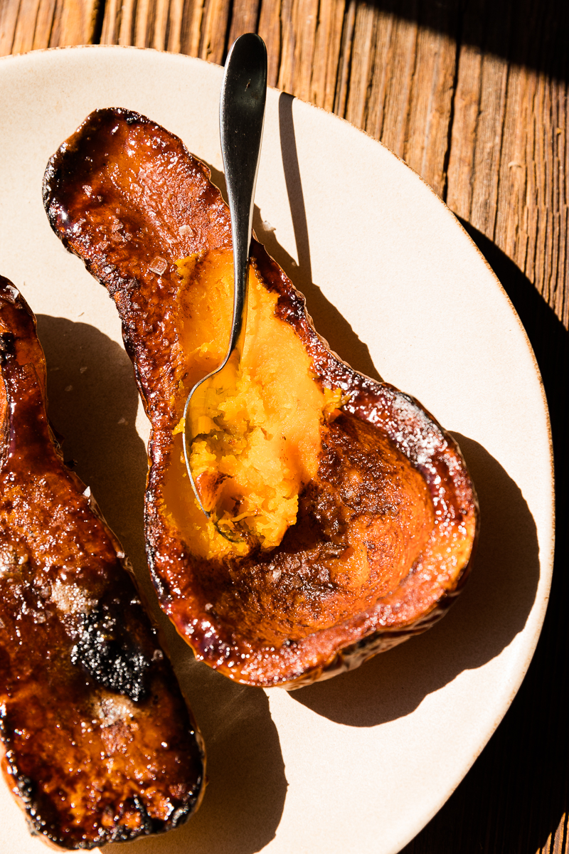 Spoon scooping out caramelized butternut squash halves.