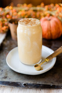 pumpkin pie protein shake in a glass cup on top of a white plate.
