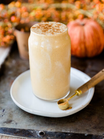 pumpkin pie protein shake in a glass cup on top of a white plate.