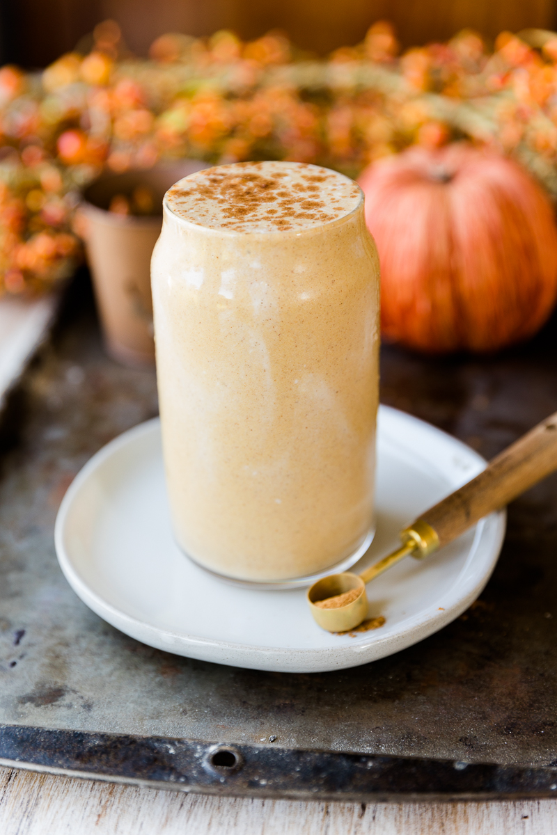 pumpkin pie protein shake in a glass cup on top of a white plate.