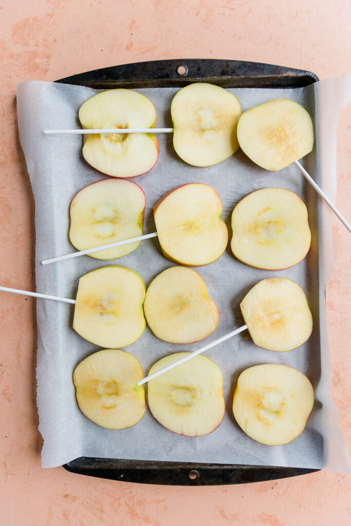 Sliced apples with cake pops sticks.