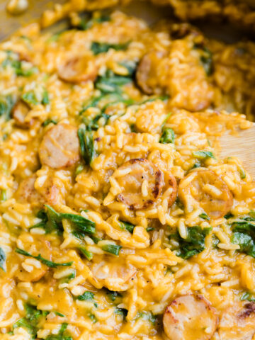 Creamy chicken sausage and rice with spinach in large pan.