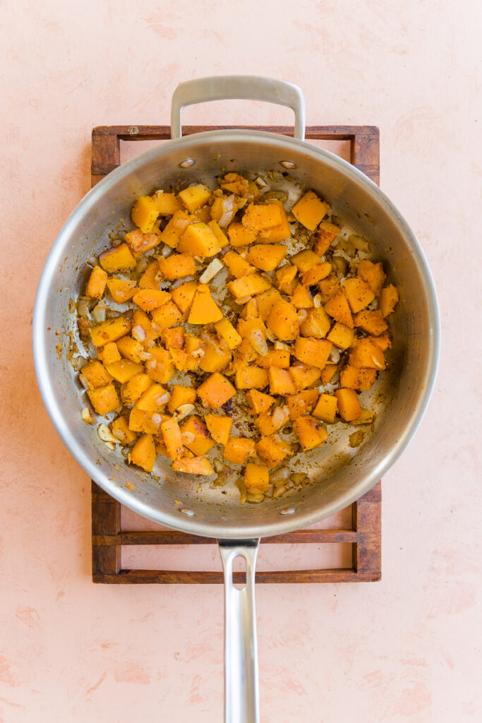Cubed butternut squash and onion cooking in a large pot.
