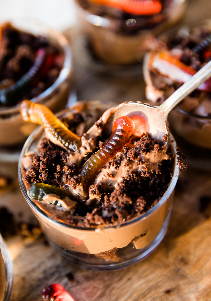 Spoon scooping out dirt cup with gummy worms.