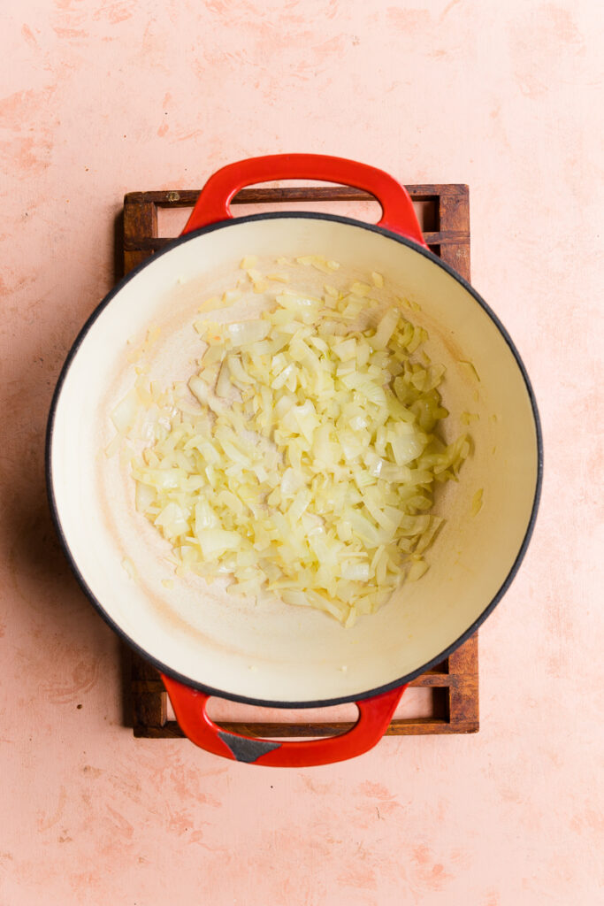 Onions and garlic cooking at the bottom of a pot.