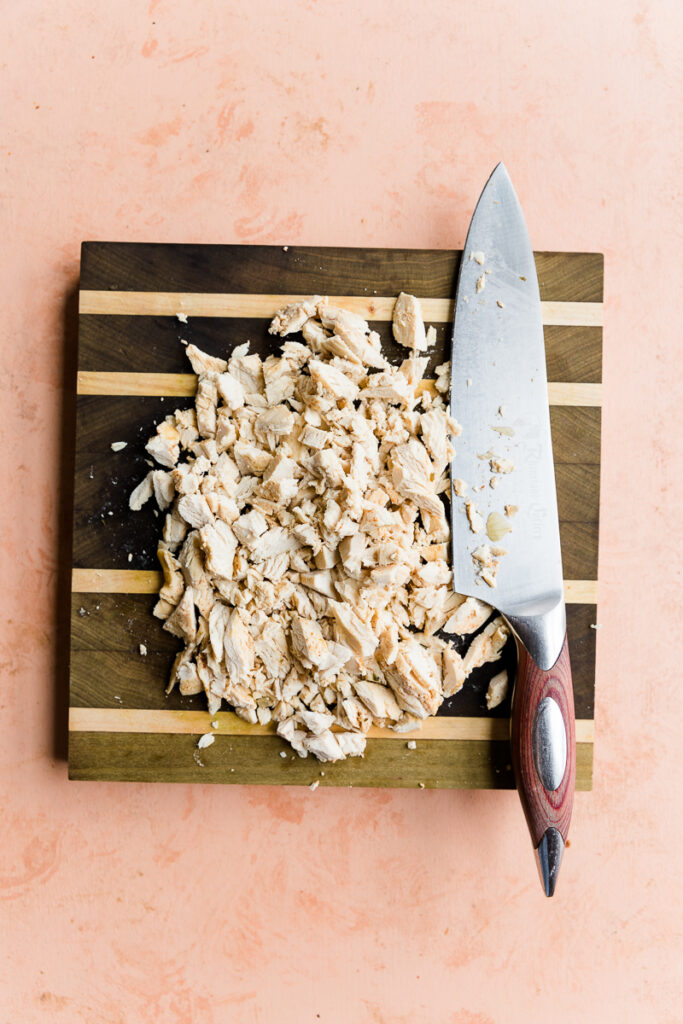 Chopped chicken on a wooden cutting board.