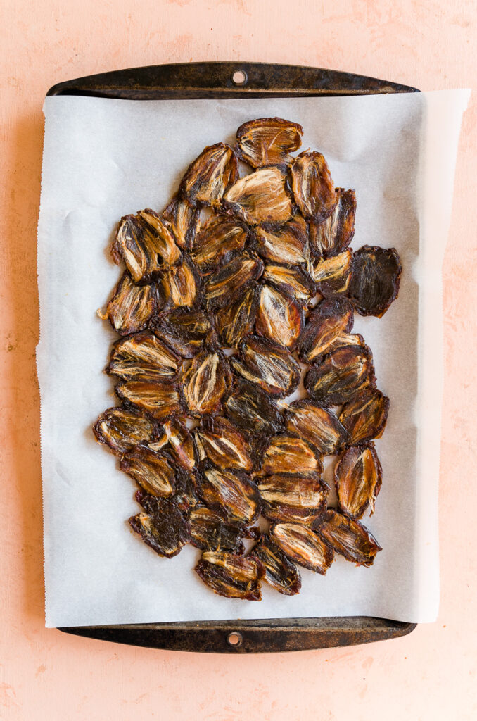 Dates flattened out on a parchment paper lined baking sheet.