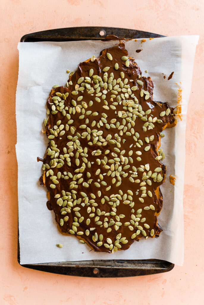 Chocolate layer spread out on the pumpkin layer with raw pumpkin seeds on top.