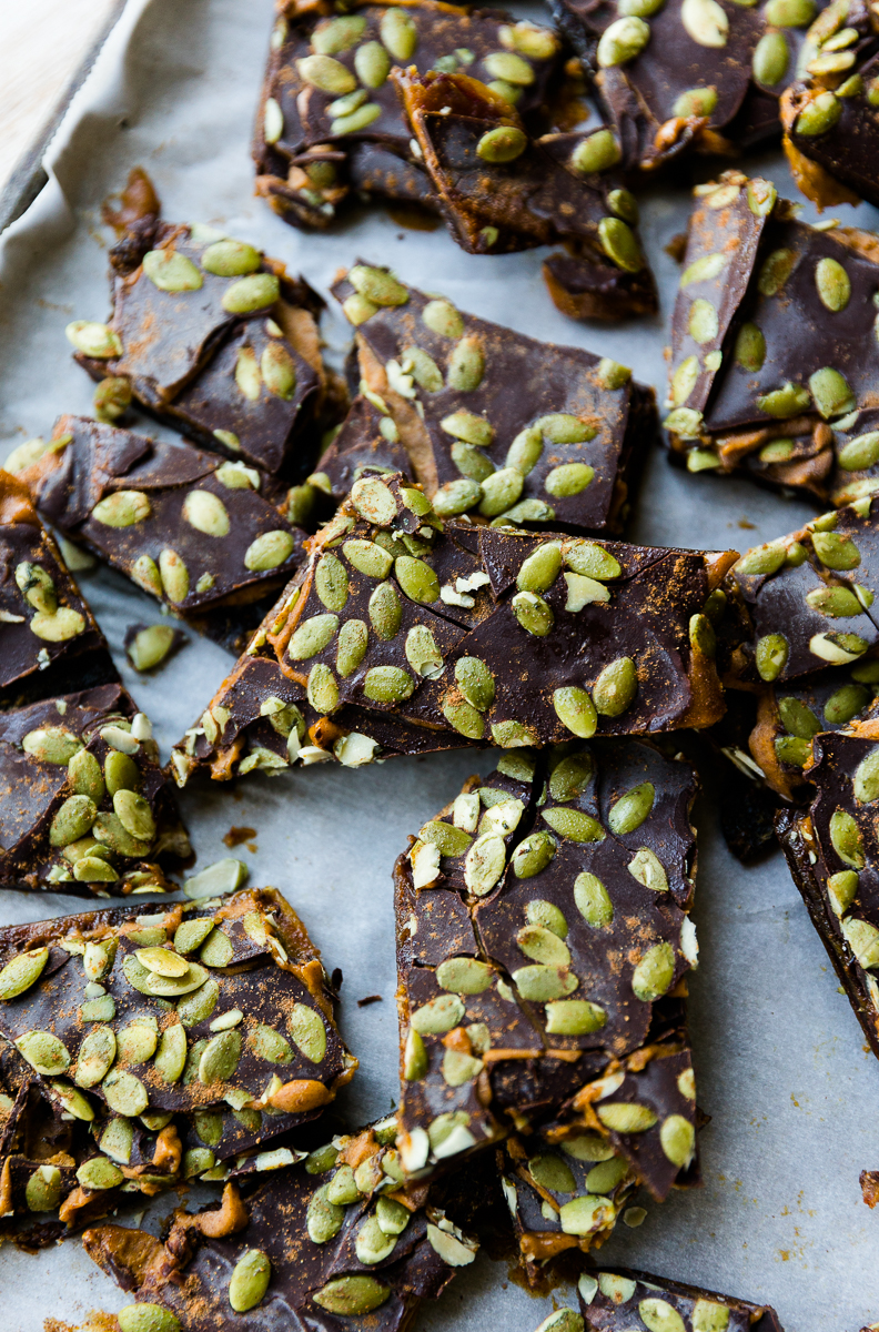 Pumpkin date bark layered on top of a parchment paper lined baking sheet.