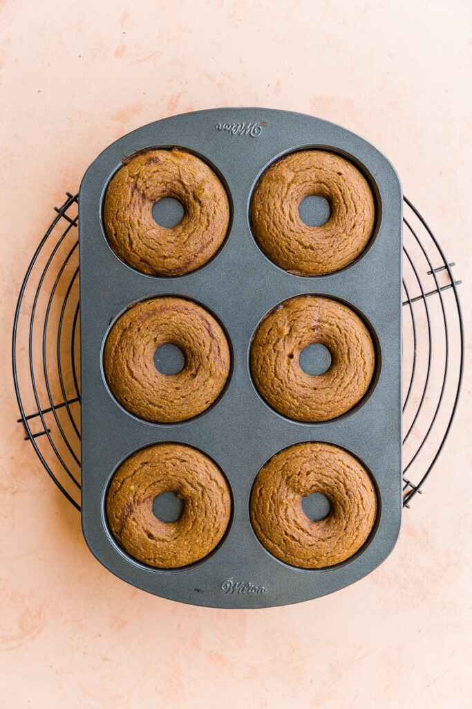 Baked donuts cooling on a rack.