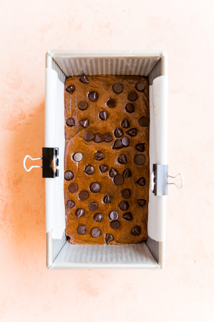 Pumpkin protein bar dough pressed into a loaf pan with chocolate chips on top.