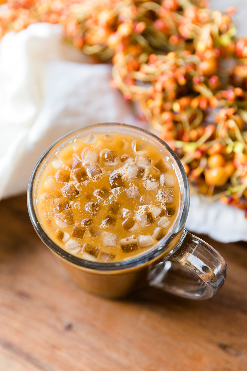 Close up picture of iced pumpkin coffee in glass mug.