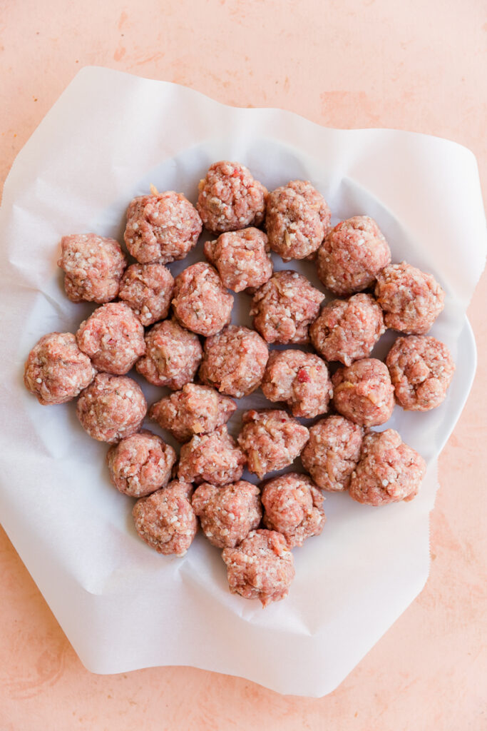 Meatballs on a parchment paper lined plate.