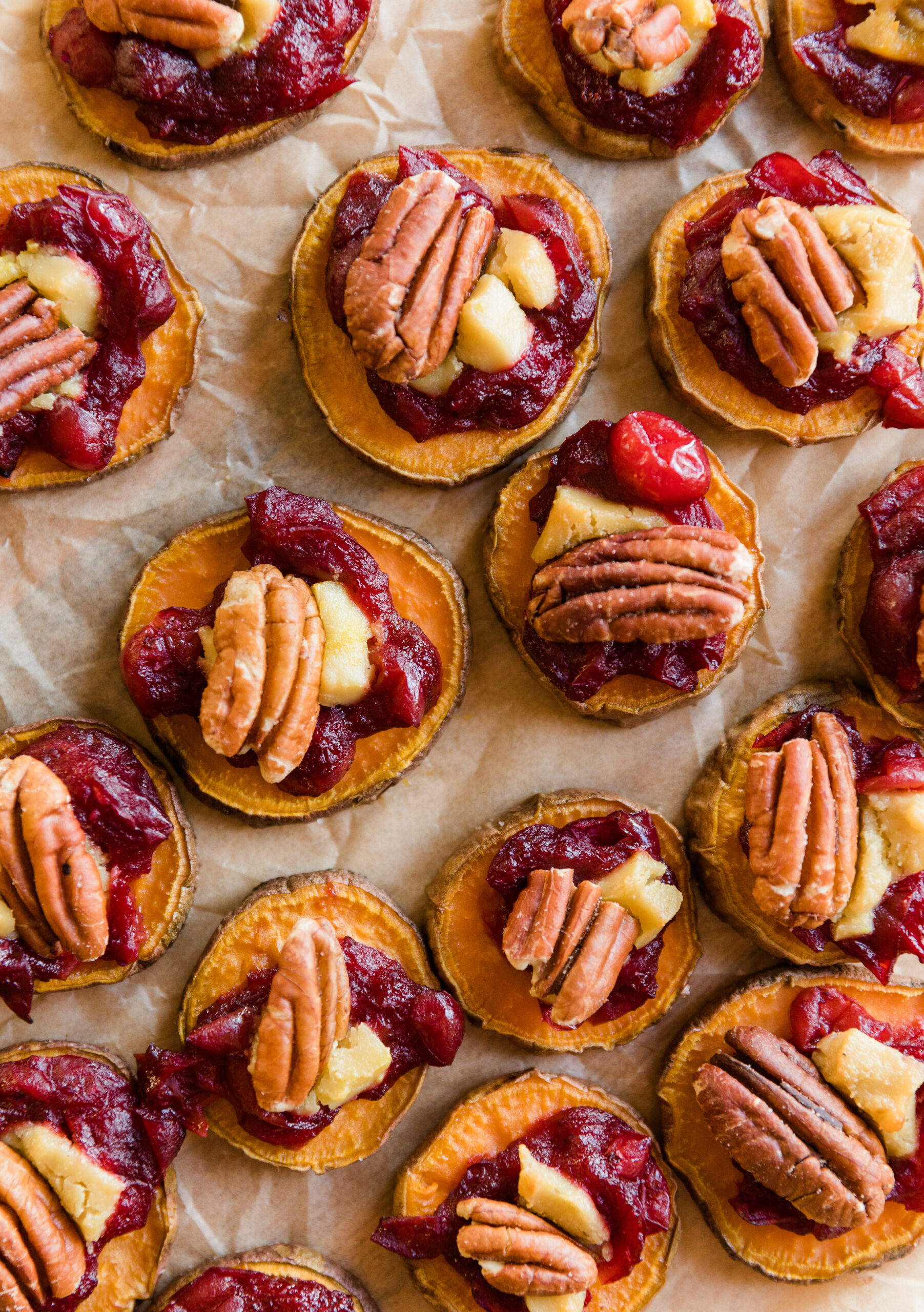 Sweet potato bites with pecans, cheese, and cranberry sauce on top.