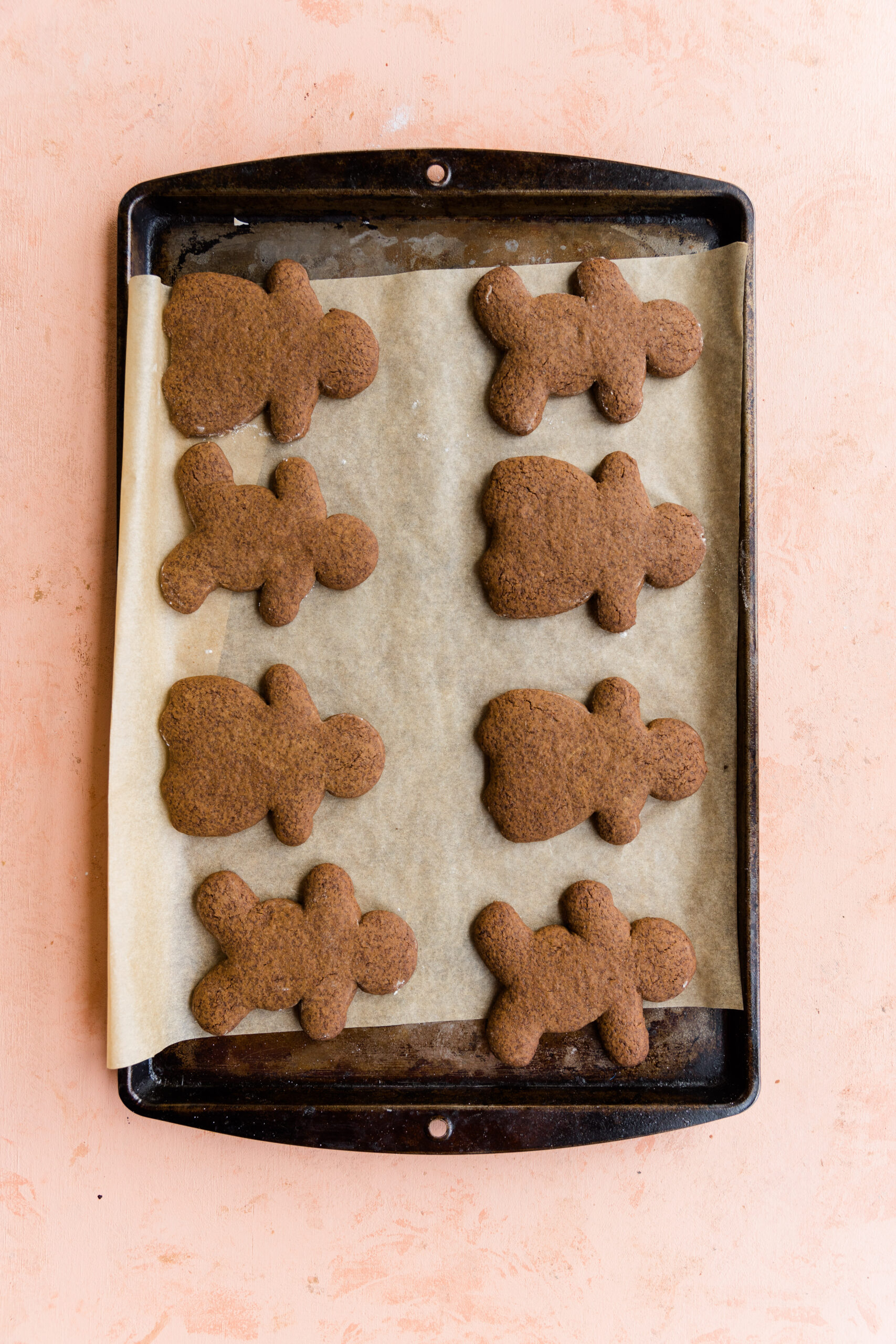Baked gingerbread cookies on a parchment paper lined baking sheet.