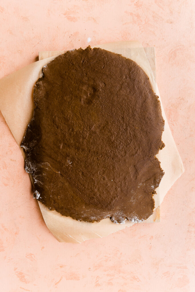 Gingerbread cookie dough rolled out on parchment paper.