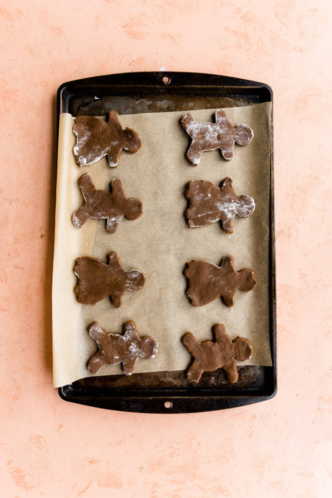 Gingerbread men cookies cut out on a baking sheet lined with parchment paper.