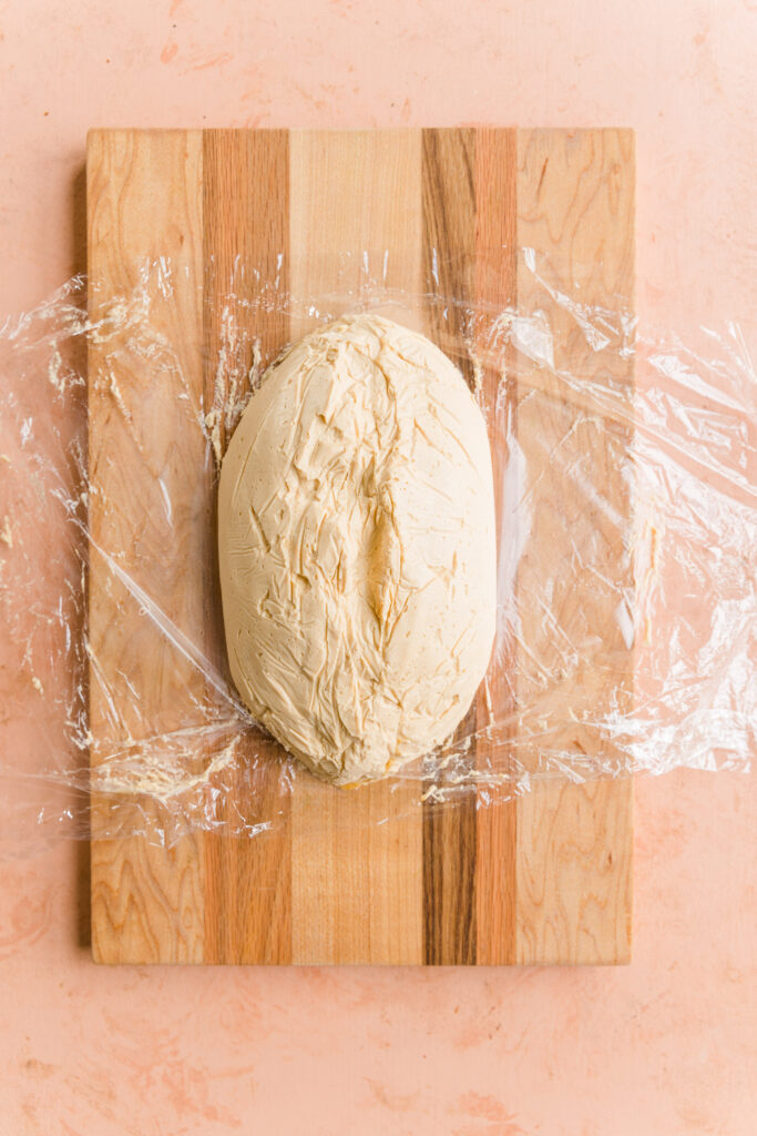 Chilled football cheese ball on cutting board.