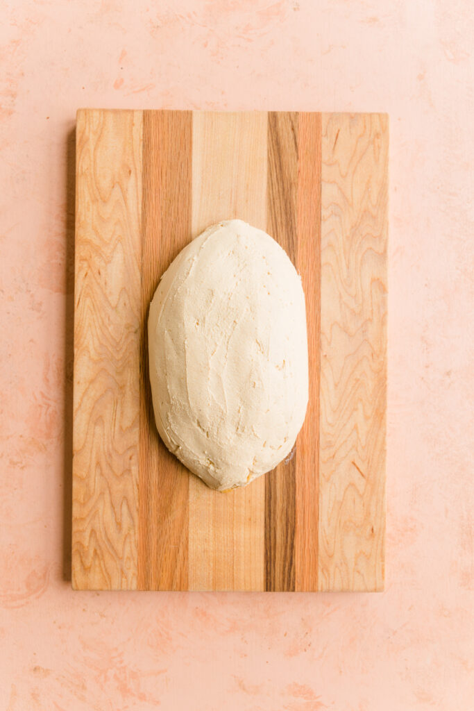 Football cheese ball smoothed and shaped on cutting board.