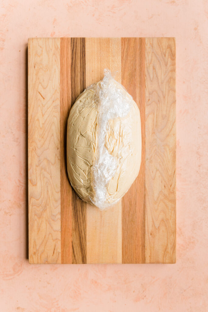 Cheese ball mixture shaped into football covered in plastic wrap.